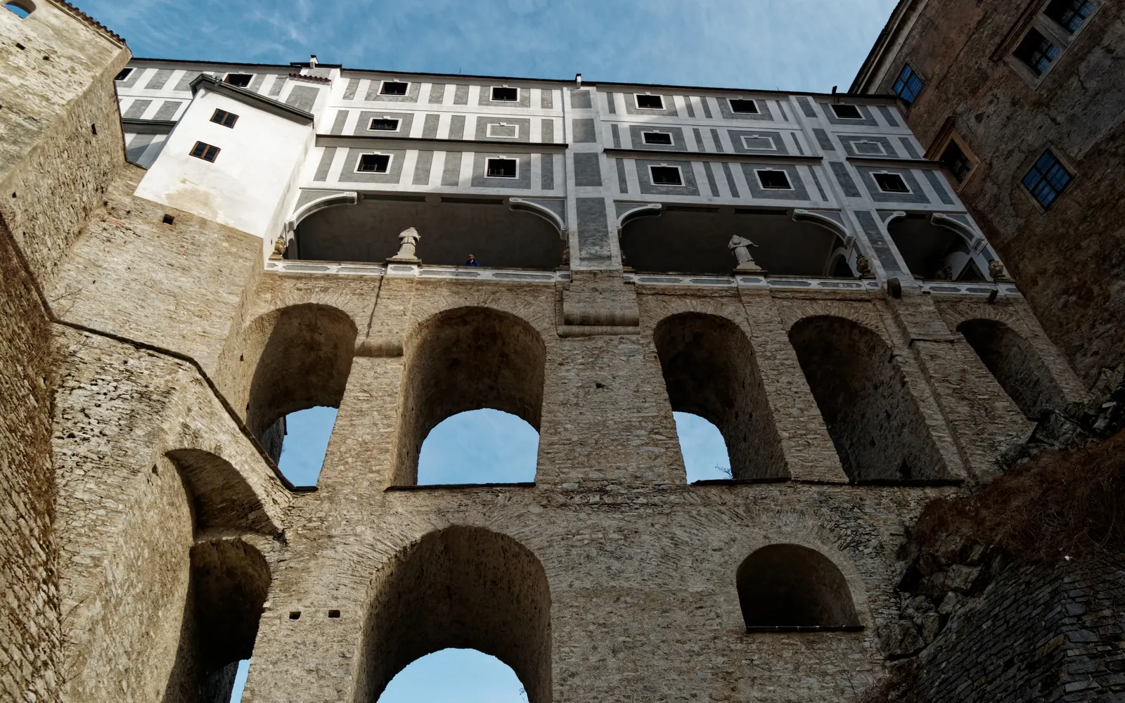 The tiered arches of the Cloak Bridge at Český Krumlov Castle seen from below